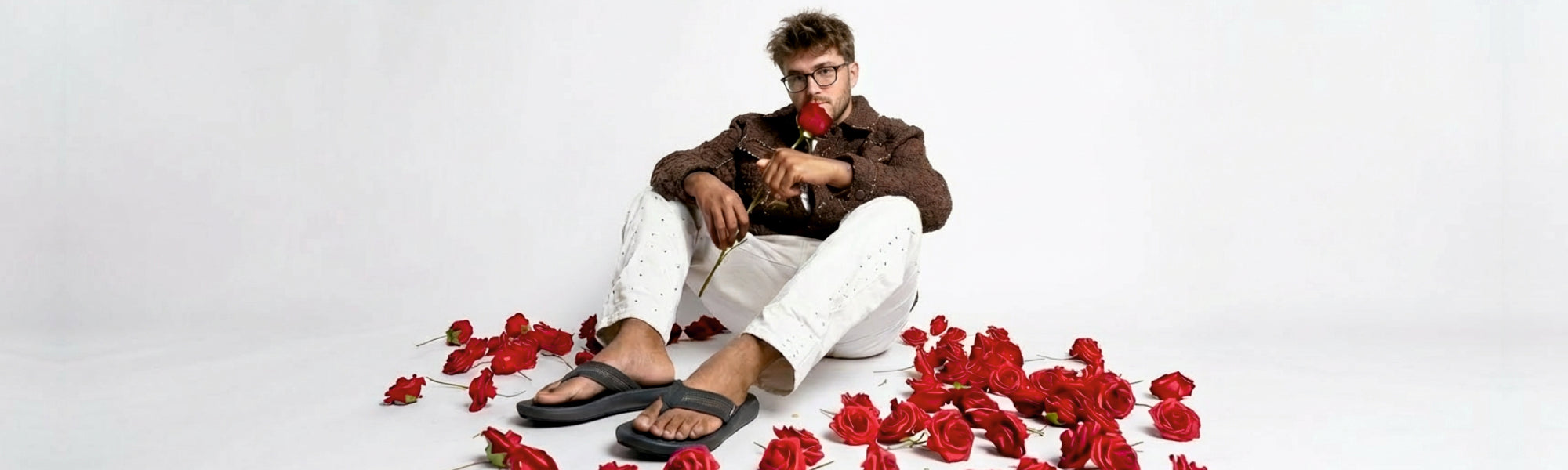 Man in tropical shirt and Toucantoes flip-flops relaxing outdoors, sipping a cold drink on a patio