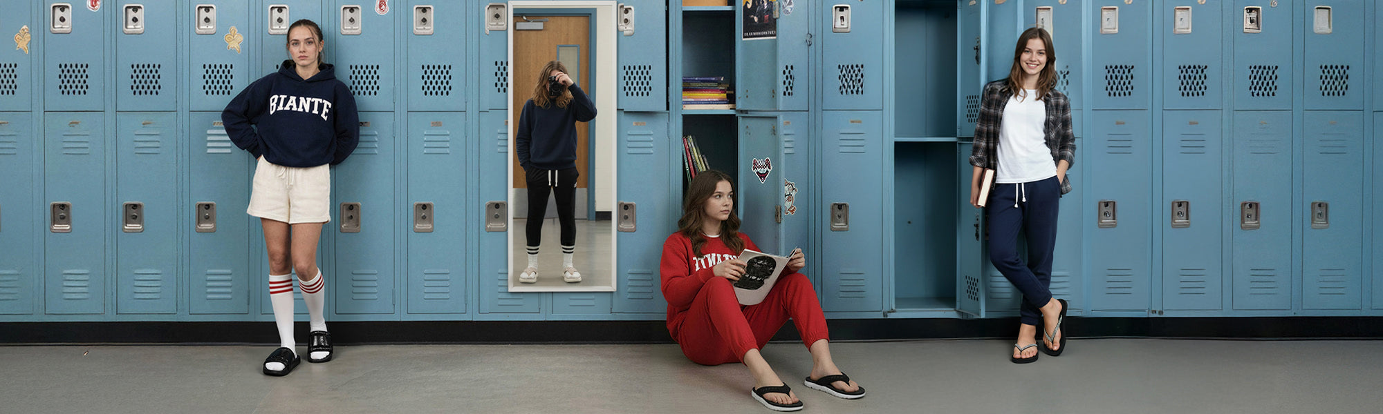 Three young women in casual loungewear by blue school lockers; one in navy hoodie, one in red outfit reading, one in plaid shirt with book