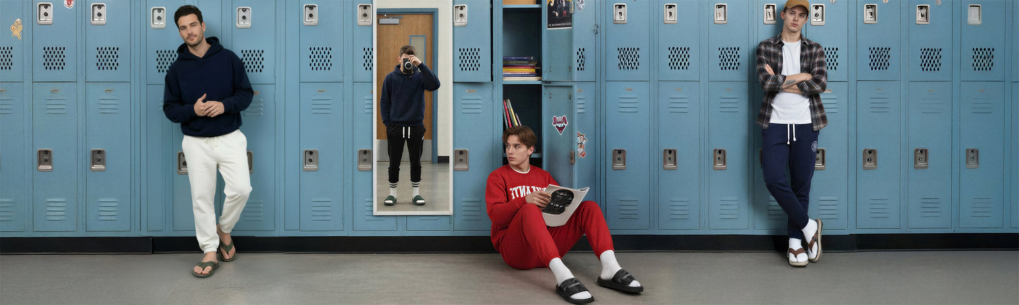 Men posing in casual loungewear and hoodies near blue school lockers, one sitting reading