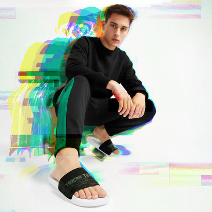Young man in black and green tracksuit crouching wearing black Toucan slides on white background with colorful glitch effect