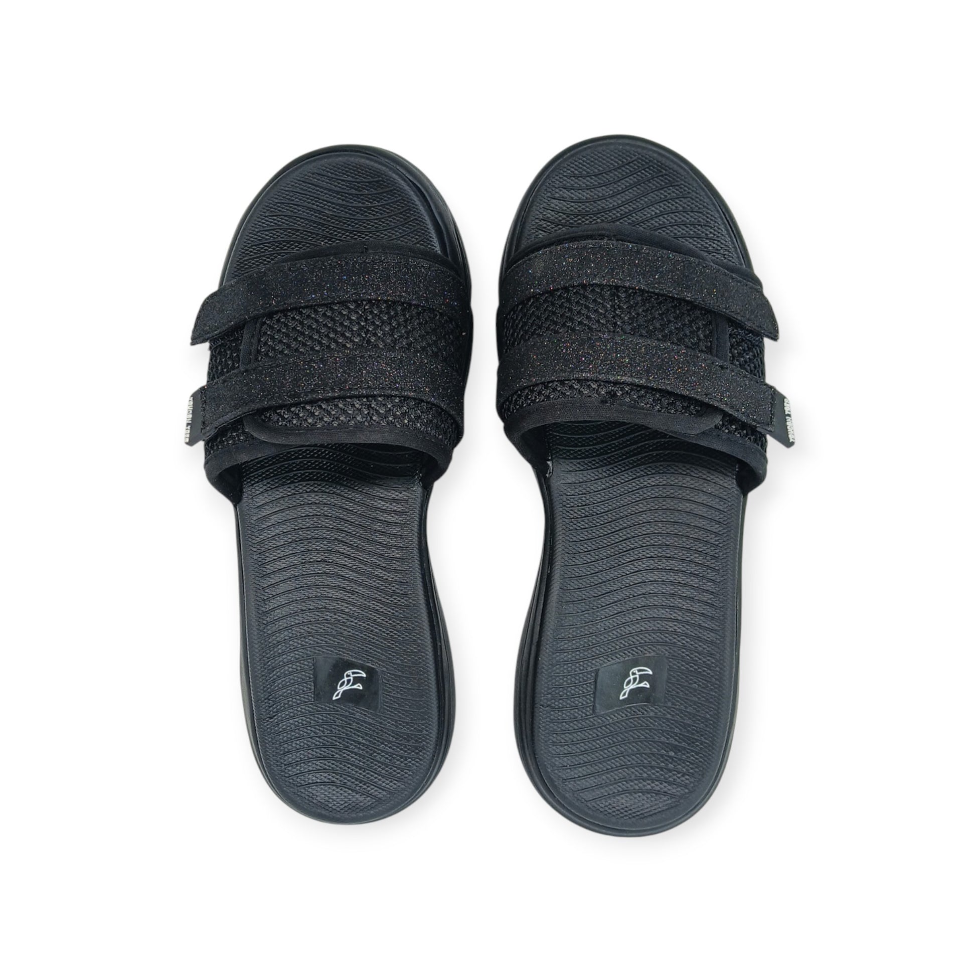 Pair of black slide sandals with textured footbeds and glittery double straps on white background