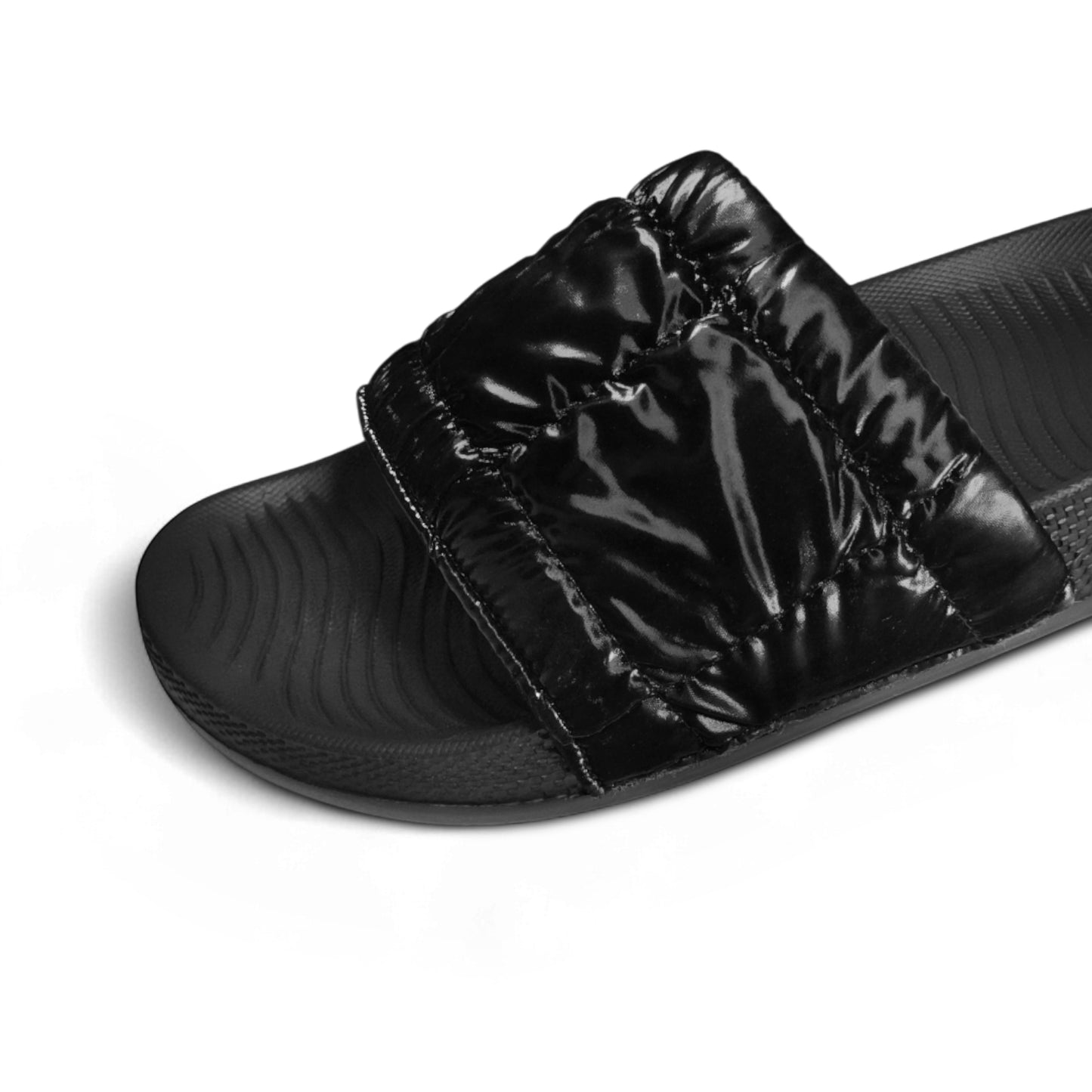 Close-up of black padded slide sandal with textured footbed on white background