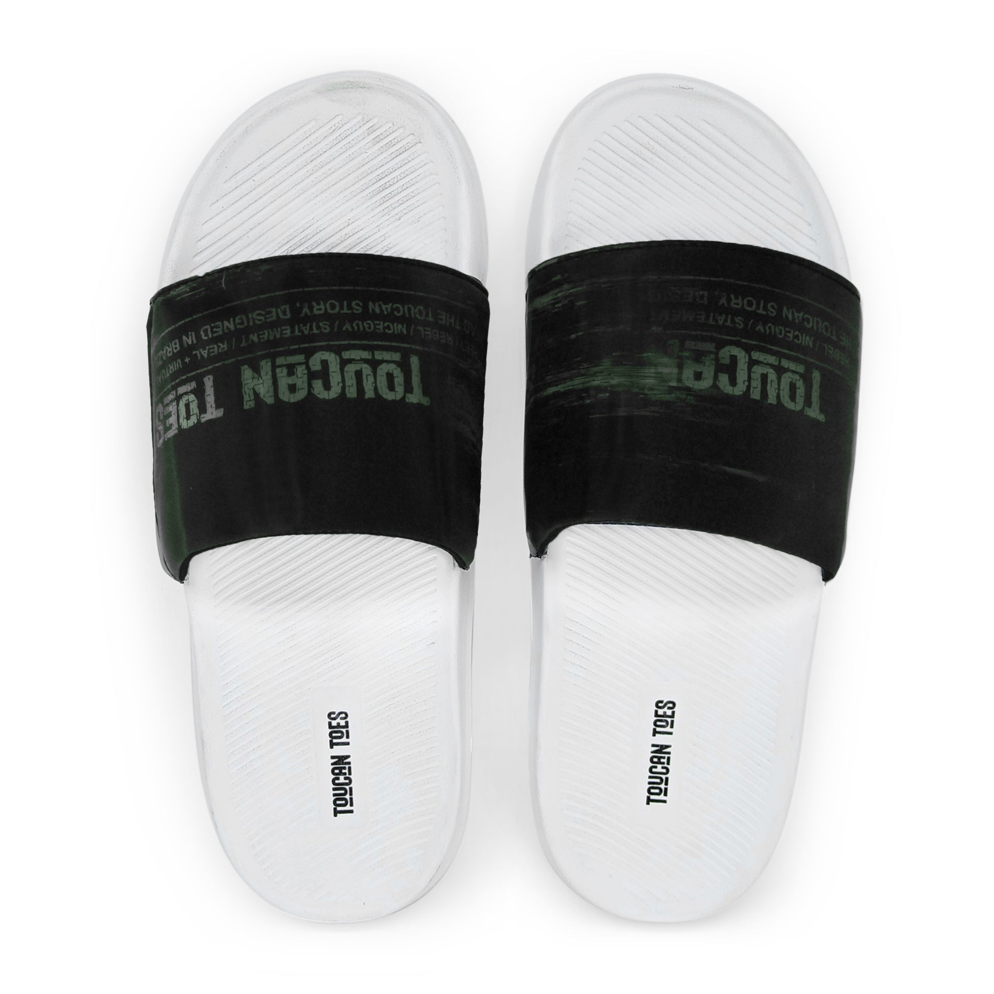 White slide sandals with black straps featuring faded Toucan Toes logo and textured footbed