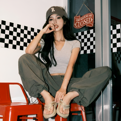 Woman in casual outfit and Toucan Toes sandals sitting indoors on red chair